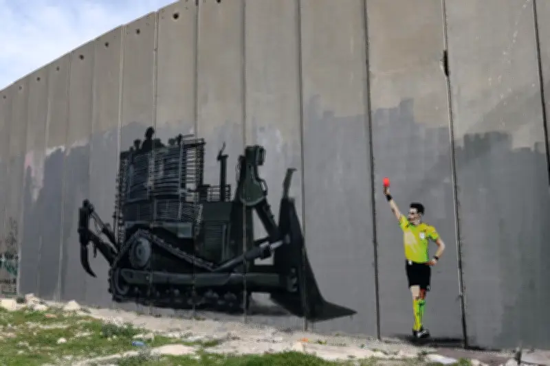 Grafiti en Belén muestra árbitro de UEFA expulsando excavadora israelí que amenaza campo de fútbol